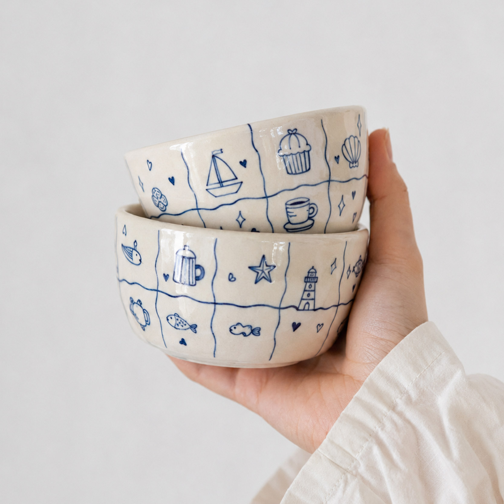 Hand hält zwei handbemalte Keramikschalen mit blauen Motiven